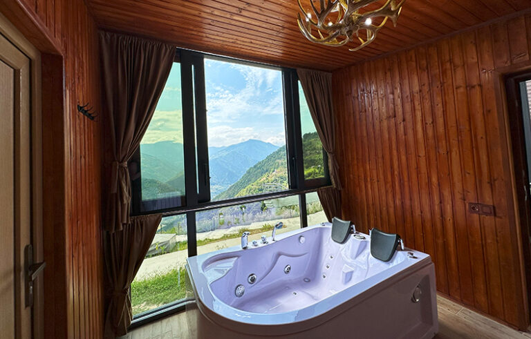 Large hot tub for two by the panoramic window with a mountain view in cabin A2 — Nika Hotel & Club