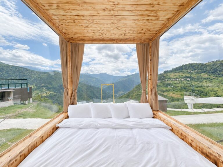 Bed in the glass cabin with panoramic windows onto the Adjara mountains by day — Nika Hotel & Club