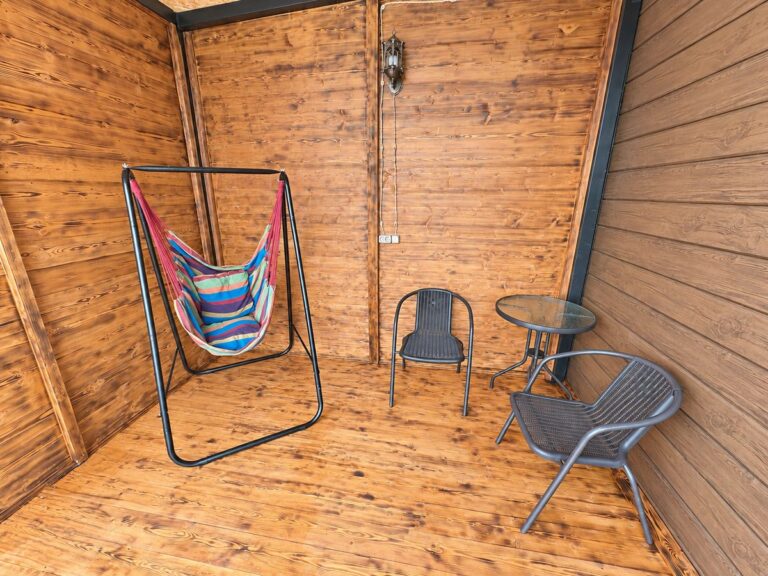 Covered veranda with a hanging hammock chair, table and chairs — Nika Hotel & Club