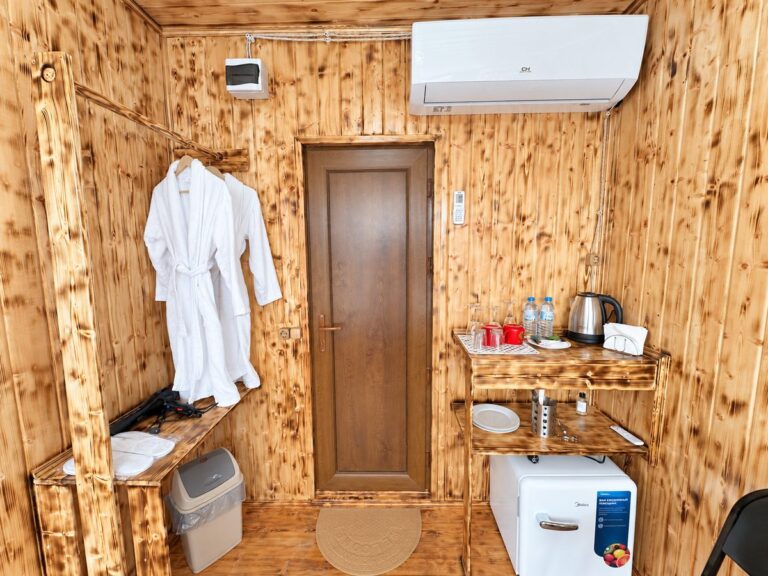 Cabin entrance: bathrobes, hairdryer, air conditioning, tea shelf and fridge — Nika Hotel & Club